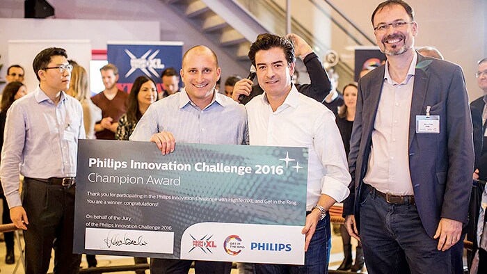 Benno Tieke stands next to two winners holding a sign at the Philips Innovation Challenge 2016.