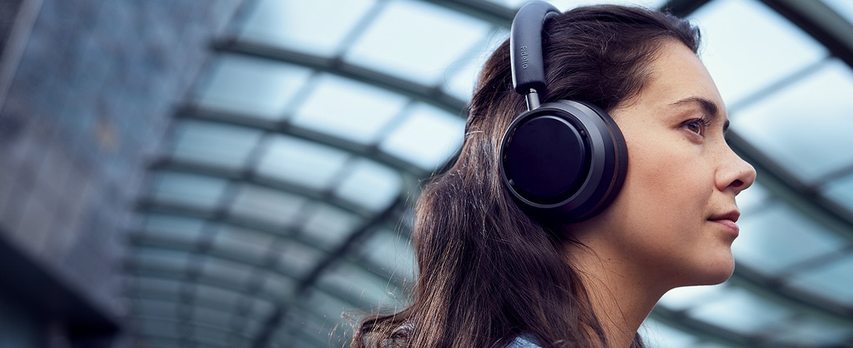  Philips L4 kulaklık kullanarak seyahatte müzik keyfi yapan kadın
