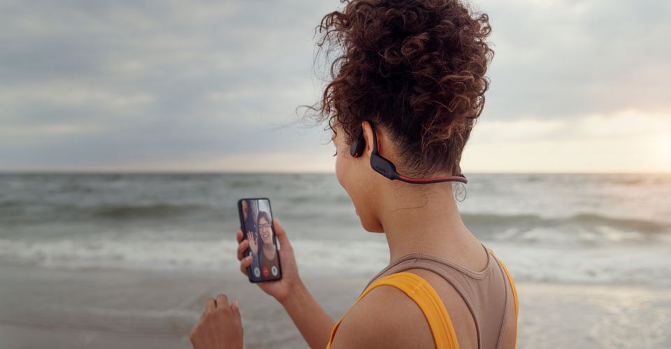 Kemik iletimli kulaklık kullanırken sahilde bir telefon görüşmesi yapan atlet