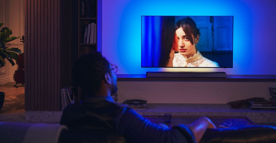 Soundbar'lı Philips Ambilight TV'nin keyfini çıkaran adam