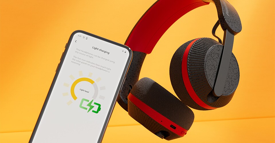 Parlak turuncu bir arka plan üzerinde, ışık şarj ekranını gösteren bir akıllı telefonun yanında Philips A6219 kulaklıklar
