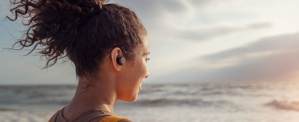 Deniz kenarında true wireless kulaklık kullanan kadın