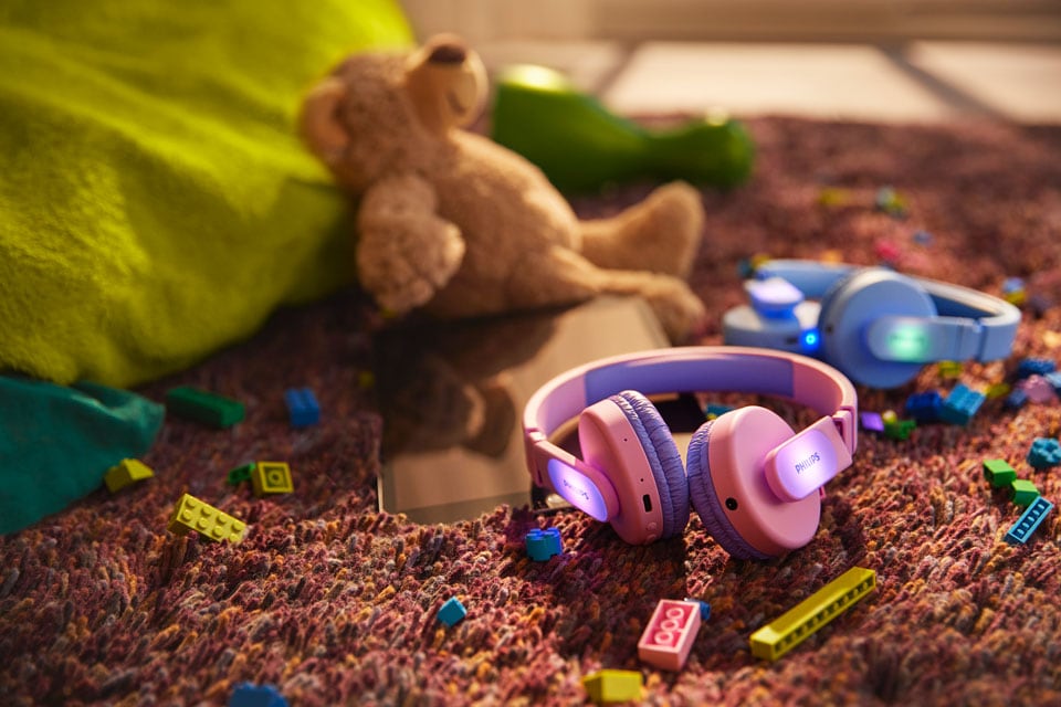 Yerde oyuncaklarla birlikte mavi ve pembe bir çocuk kulaklığı
