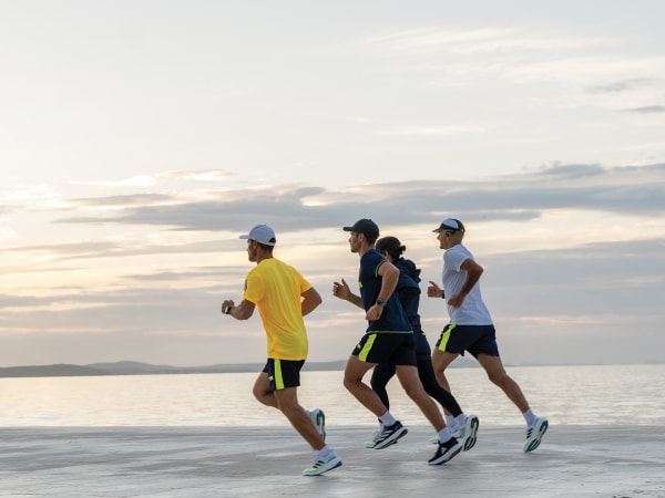 Koşuya katılan dört kişi plajda beraber koşuyor.